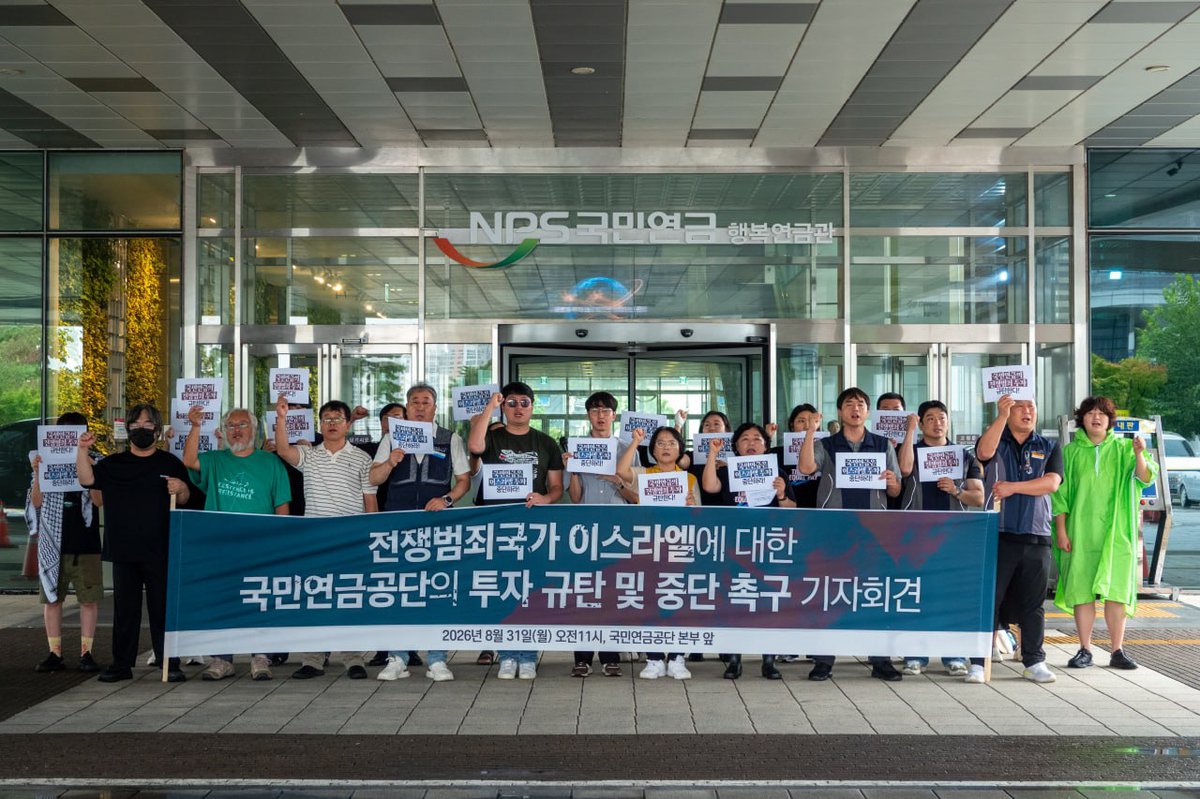 20명 이상의 사람들이 국민연금공단의 전쟁범죄국가 이스라엘 투자 규탄 및 중단 촉구 기자회견 현수막을 들고 기자회견을 하고 있다.